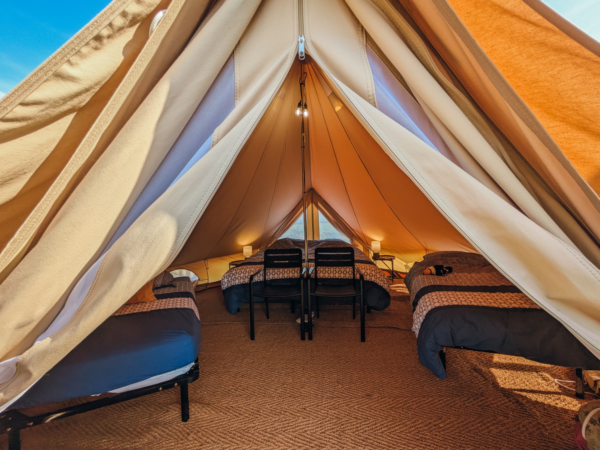Détail chaleureux à l’intérieur d’une tente glamping avec lampe et tapis