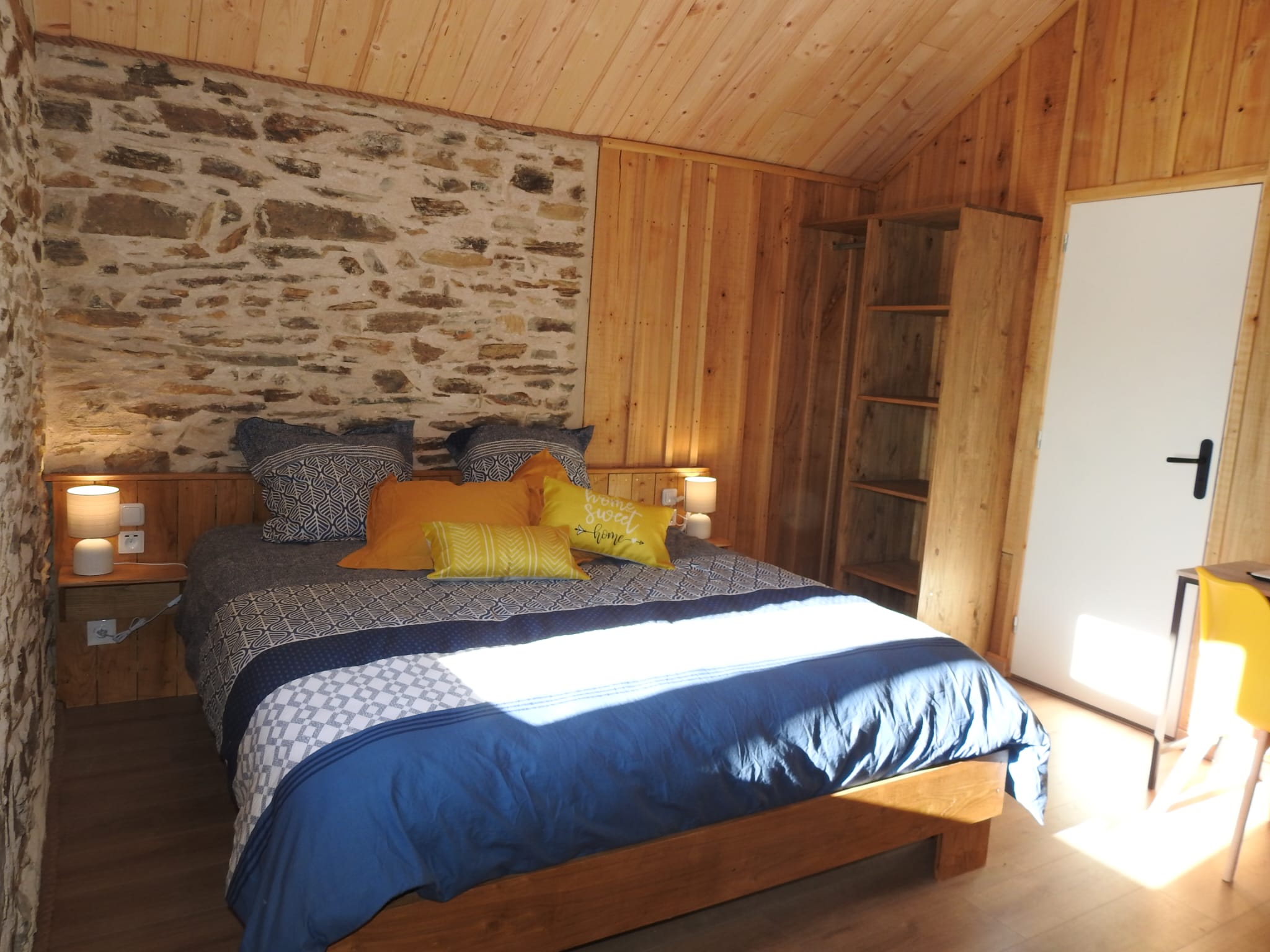 Lit king dans la Chambre Plume avec murs en pierre et lambris bois